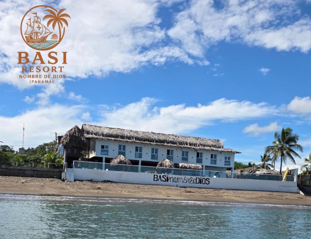 a building on the beach next to the water at Basi Resort in Nombre de Dios
