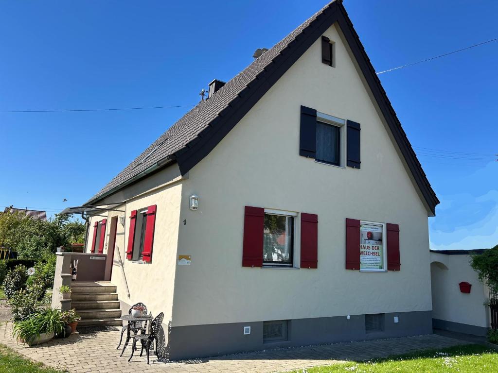 a white house with red shuttered windows and a patio at Ferienhaus bei Lauingen, mit Sauna und Gartenlounge in Veitriedhausen