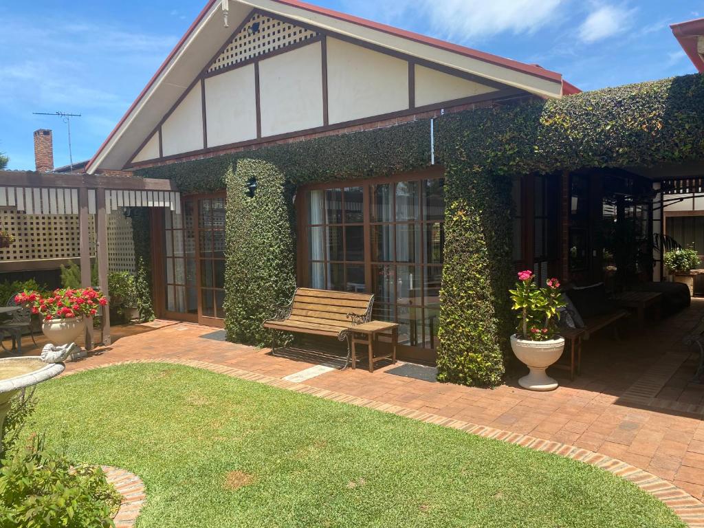 a house with a wooden bench in a yard at Ciara's Cottage CC'S in Illawong