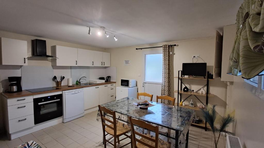 a kitchen with a table and chairs and a kitchen with white cabinets at Hébergement dans le vignoble du Mâconnais in Azé