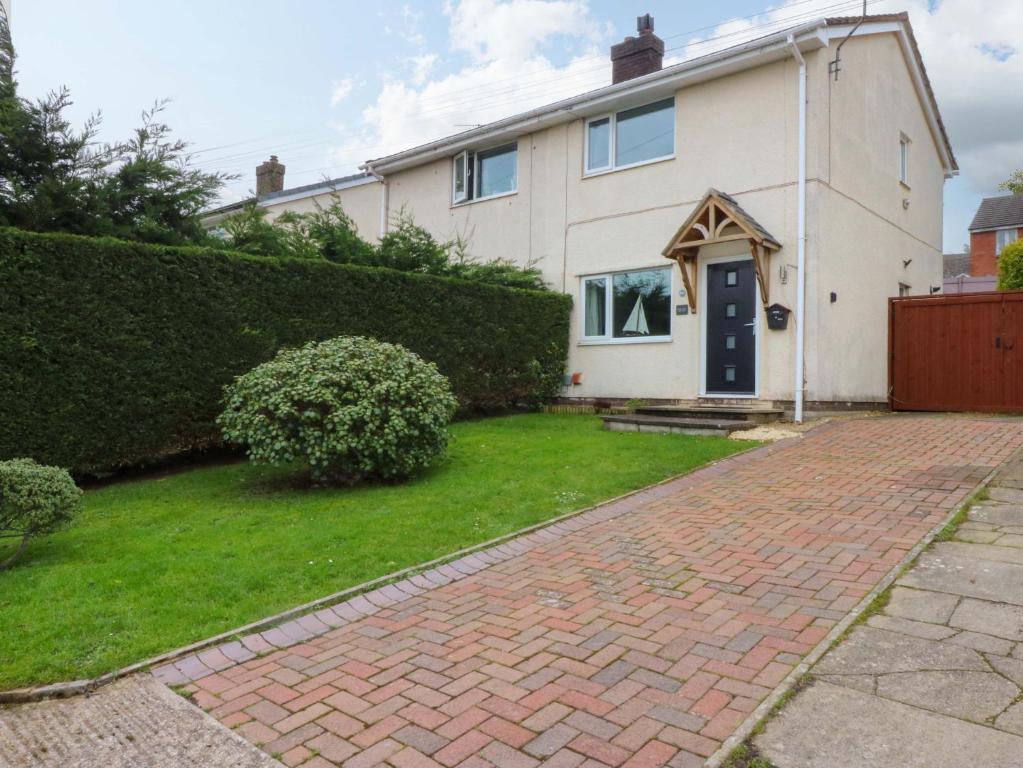 a white house with a brick driveway at Pebbles Reach in Colwyn Bay