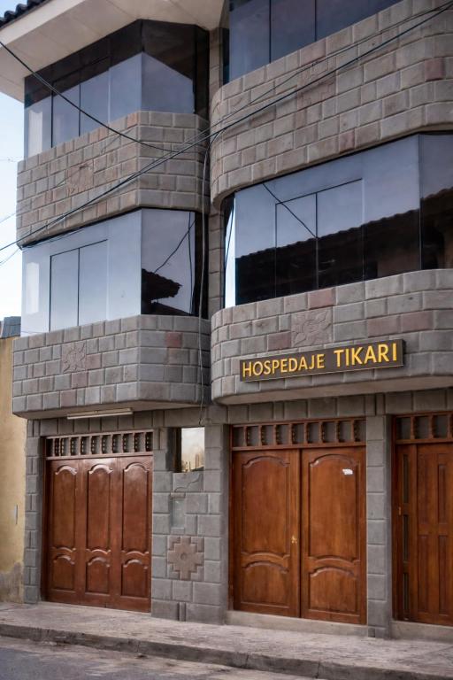 a building with two wooden doors and windows at Hospedaje Tikari in Chincheros