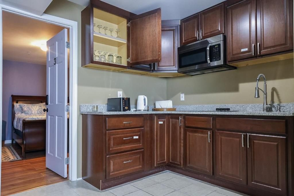 a kitchen with wooden cabinets and a microwave at Stylish Studio Escape - Calm & Convenient Lanham in Lanham