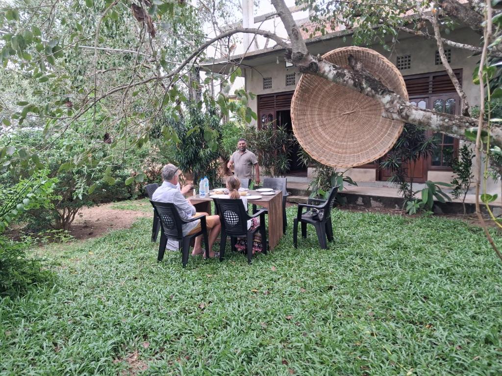 a man and a woman sitting at a table in a yard at Pasikuda Shalom Echo Villa in Palayadithona