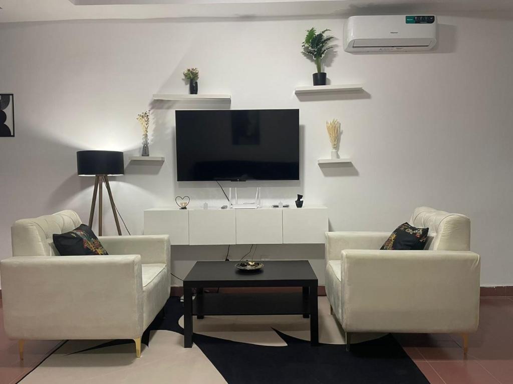 un soggiorno con due sedie e una TV a schermo piatto di Residence Nelo a Abidjan