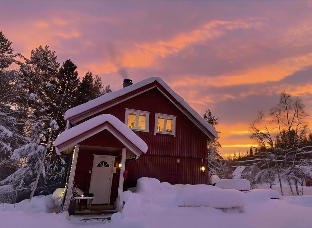 a small red house in the snow with a sunset at Landgård Feriehus, Trysil sentrum, only a 5 minutes drive in Trysil
