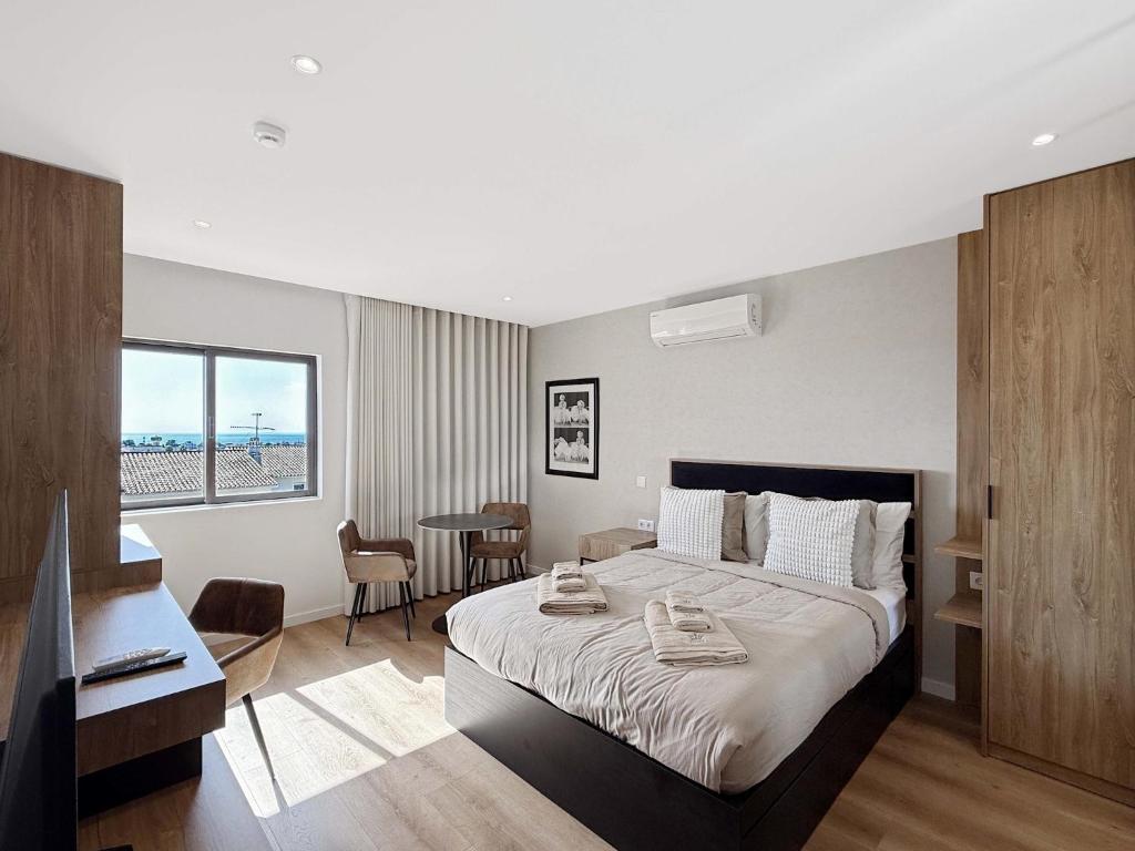 a bedroom with a large bed and a table and chairs at Ocean Breeze Rooms, Albufeira in Albufeira