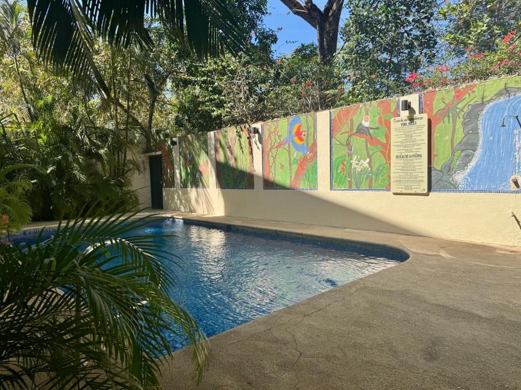 a swimming pool next to a wall with a mural at Tama Magico in Tamarindo