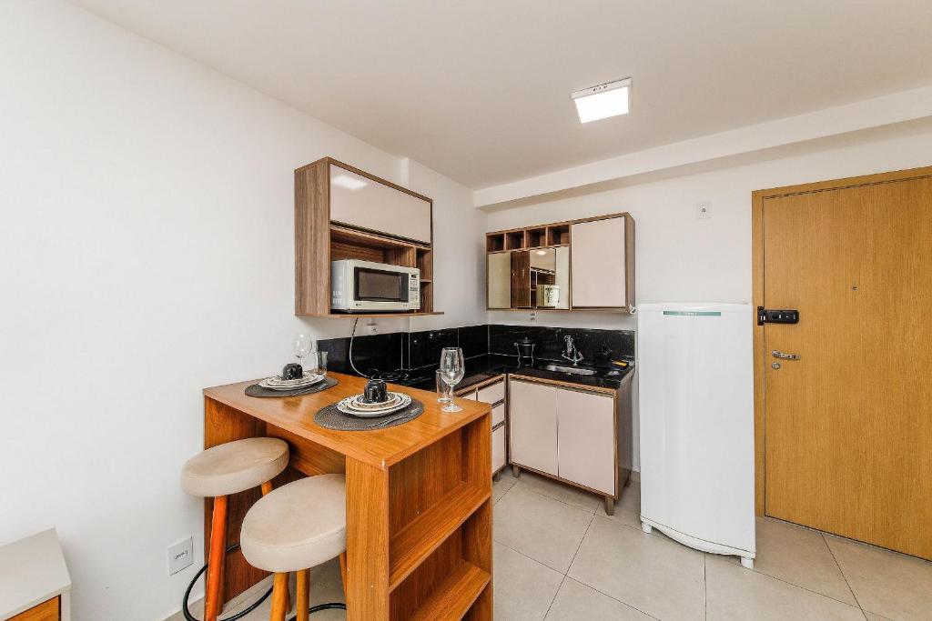a kitchen with a wooden table and a refrigerator at Studio Harmonia Ar Cond/Centro/Piscina/Academia in Juiz de Fora