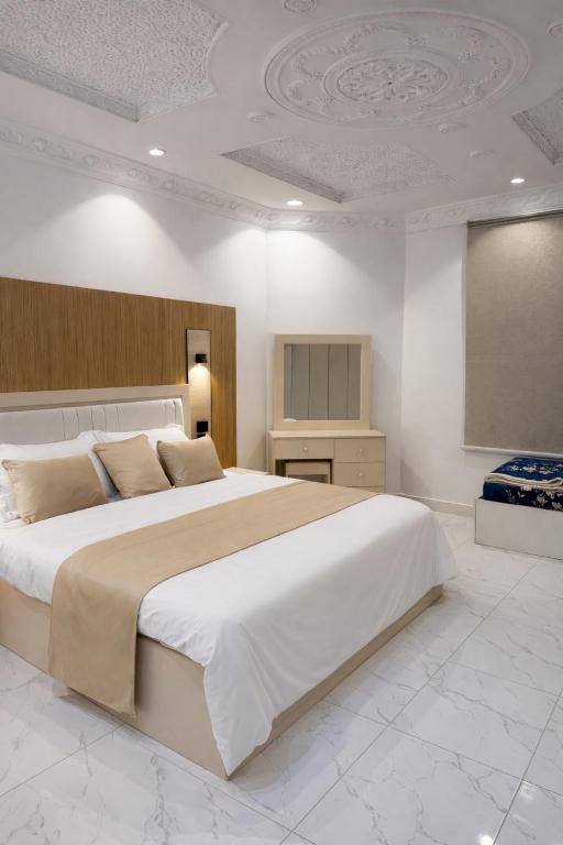 a bedroom with a large white bed and a tv at النبلا الذهبي in Medina