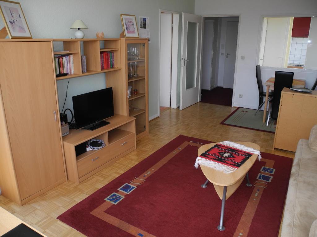 ein Wohnzimmer mit einem Sofa, einem TV und einem Tisch in der Unterkunft FeWo Bonn Sejour - Nähe UN-Campus u. WCCB in Bonn