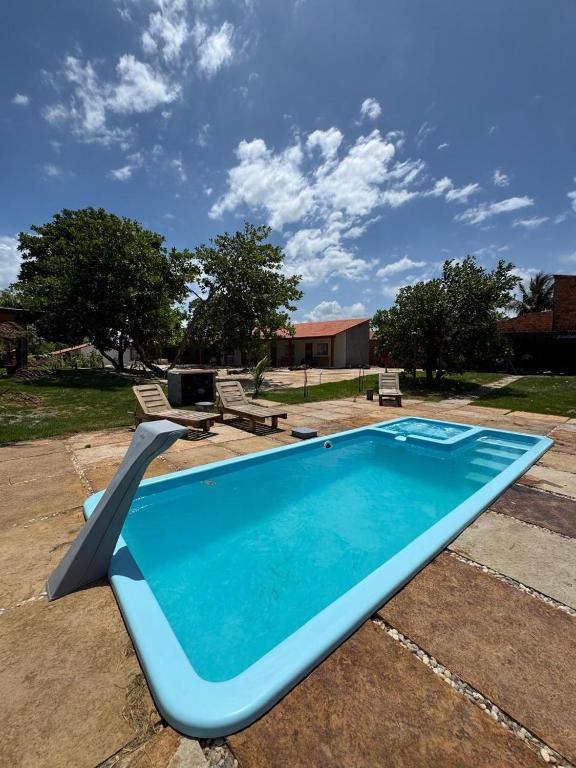 a blue swimming pool in a yard with two benches at Pousada Cajueiro Do Sol in Barreirinhas
