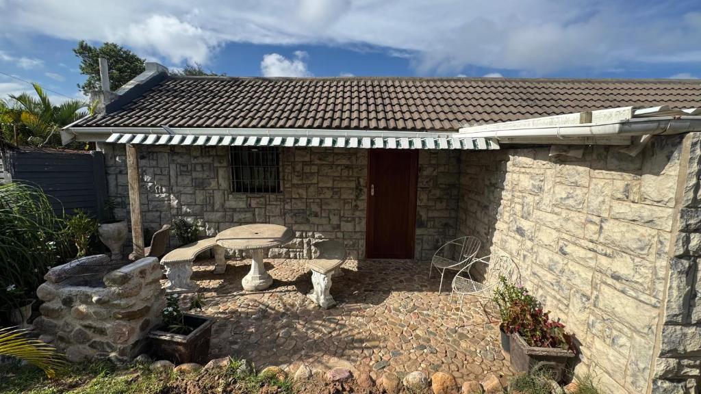 a small stone house with a table and a patio at Ahava Accommodation in Scottburgh