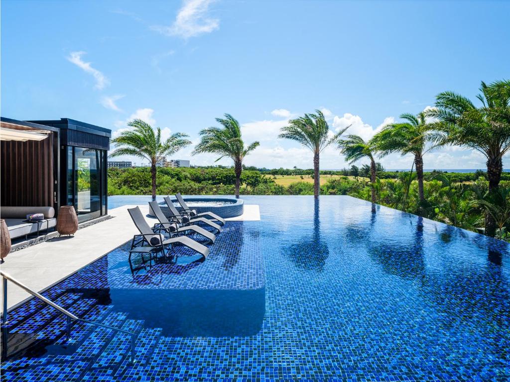 a swimming pool with lounge chairs and palm trees at seven x seven ISHIGAKI in Ishigaki Island