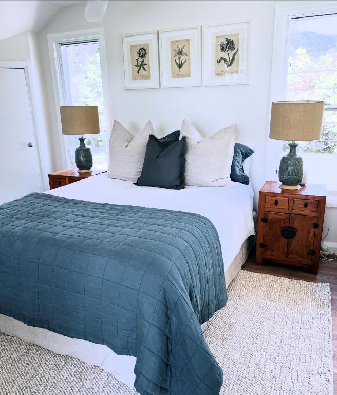 a bedroom with a bed with a blue blanket and two lamps at Wyobie Kangaroo Valley Treehouse in Kangaroo Valley