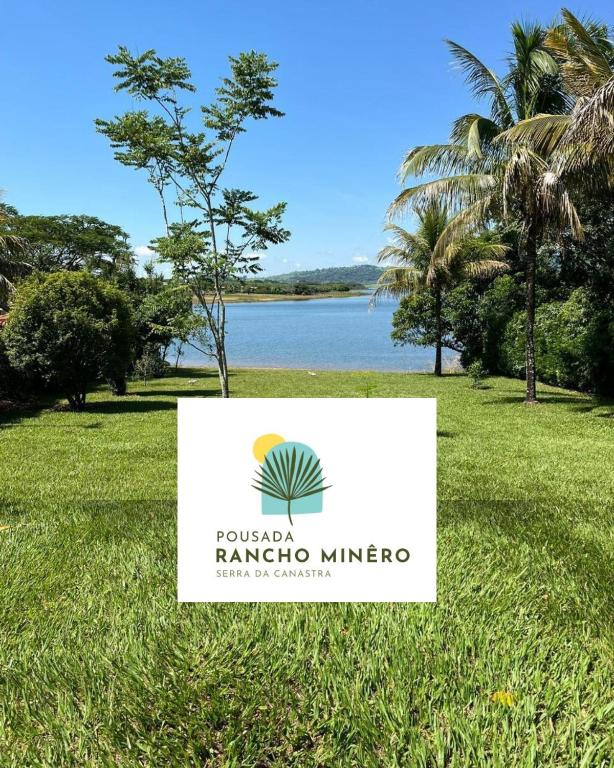 a sign in the grass in front of a lake at Pousada Rancho Minêro in Delfinópolis