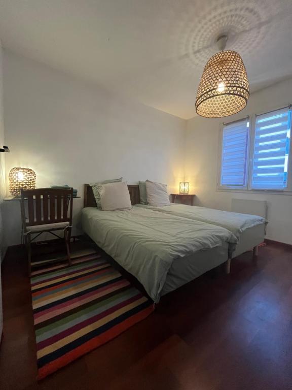 a bedroom with a large bed and a chair at Chambres chez l'habitant - Les jardins du Bil Toki in Arbonne