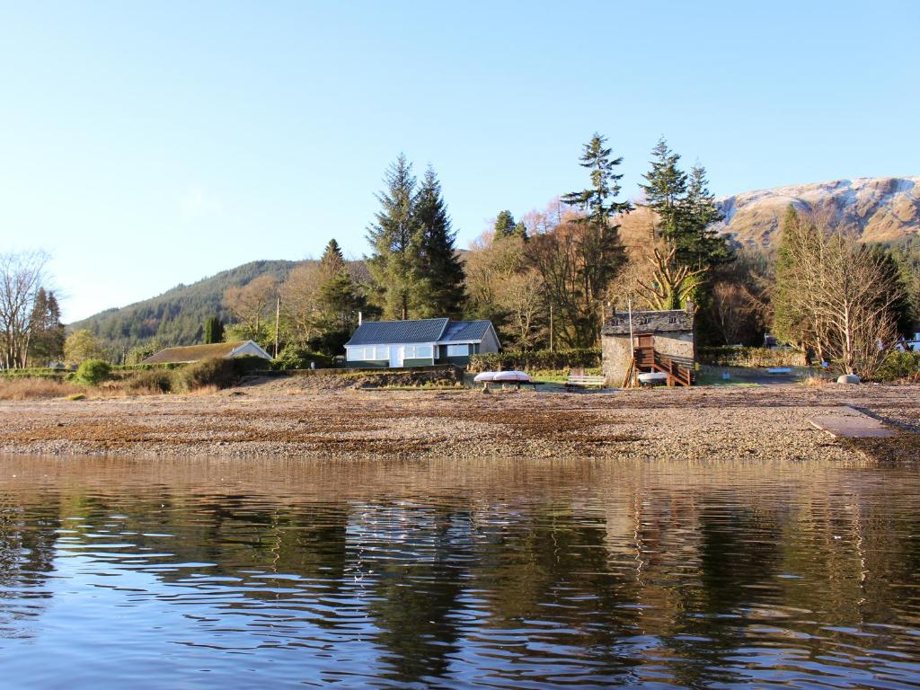 a house on the shore of a body of water at The Heron in Ardentinny