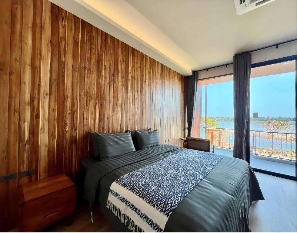 a bedroom with a bed with a wooden wall at บ้านเคียงสะหวัน in Muang Phaluka