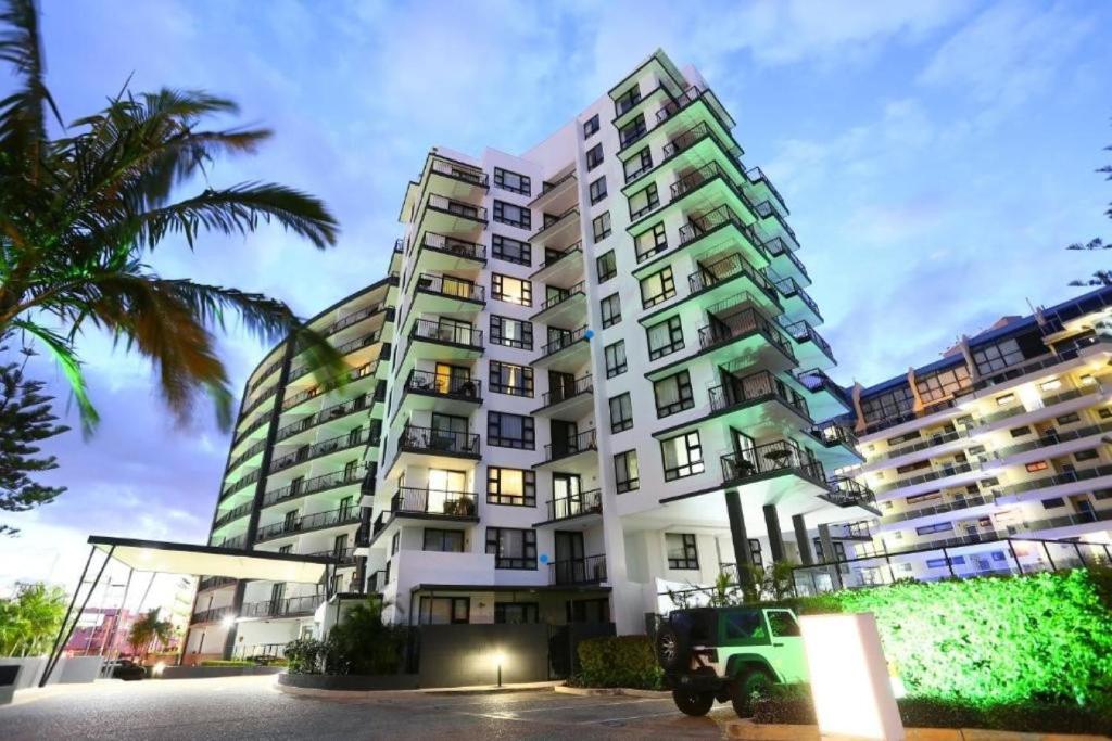 a large apartment building with a green jeep parked in front at Neptune Resort in Gold Coast