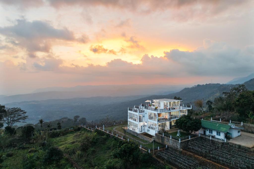 a building on a hill with a sunset in the background at Villa Rosaria - Framed by Nature, Finished with Luxury in Beragala