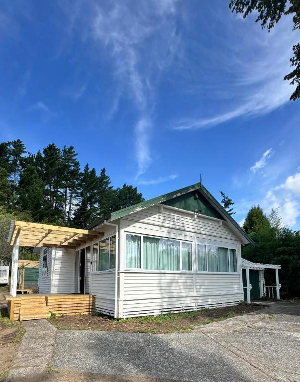 a small white house with a porch at Gosling Grove Hideaway in Turangi