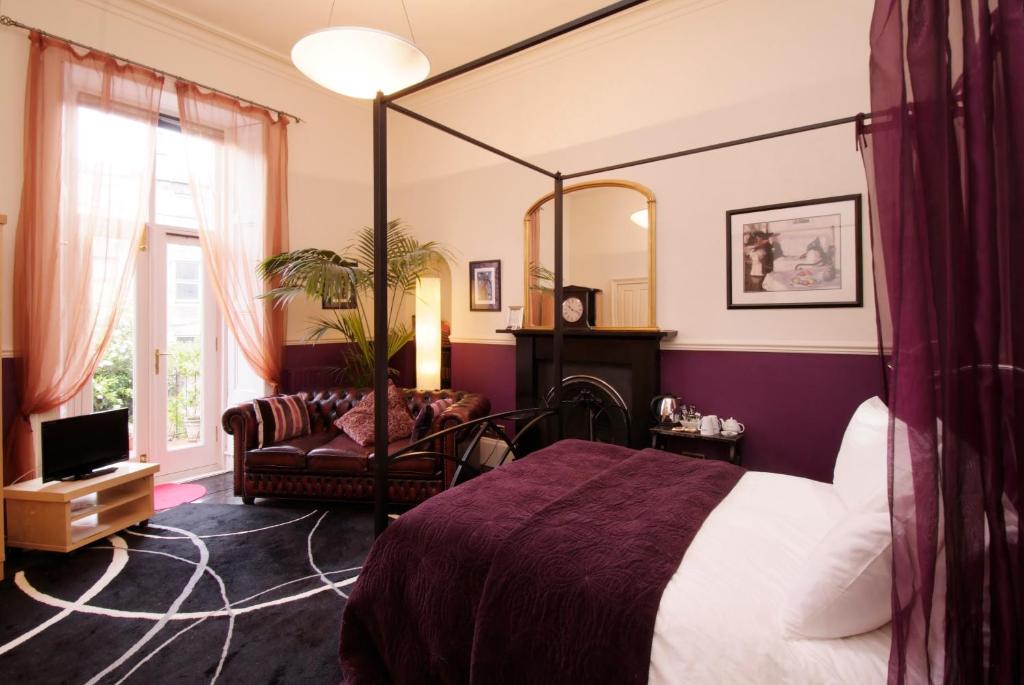 1 dormitorio con cama, silla y espejo en Southside Guest House, en Edimburgo