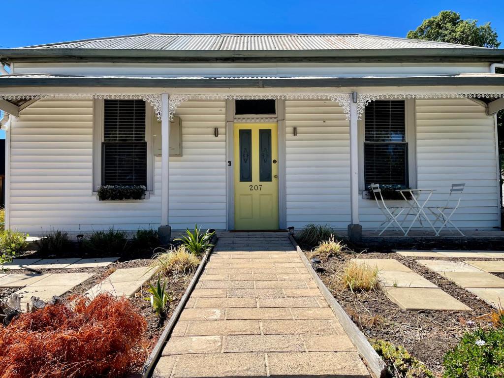 a white house with a yellow door and a porch at Pet Friendly Cottage on Large Sunny Block & 5 mins-CBD in Canadian