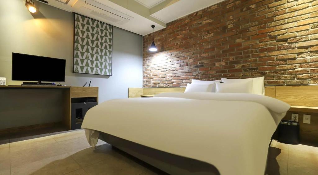 a bedroom with a white bed and a brick wall at 호텔 페르소나 in P'ungnyŏn-gol