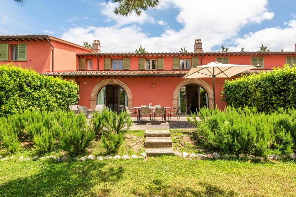 an exterior view of a house with an umbrella at Historic Farmhouse Between Two Tuscan Valleys in Trequanda