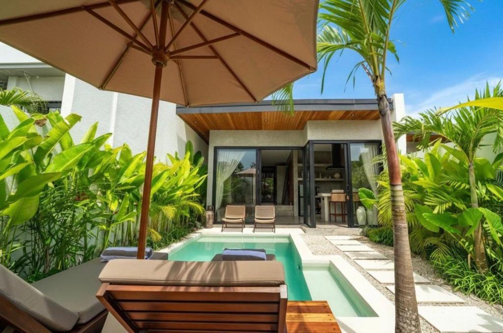 a villa with a swimming pool and an umbrella at Atol Villas in Uluwatu