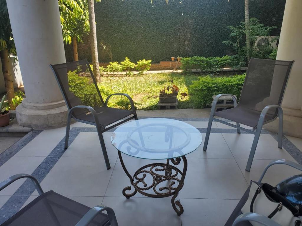 a glass table and two chairs on a patio at Casona Blanca Guesthouse in Chinandega