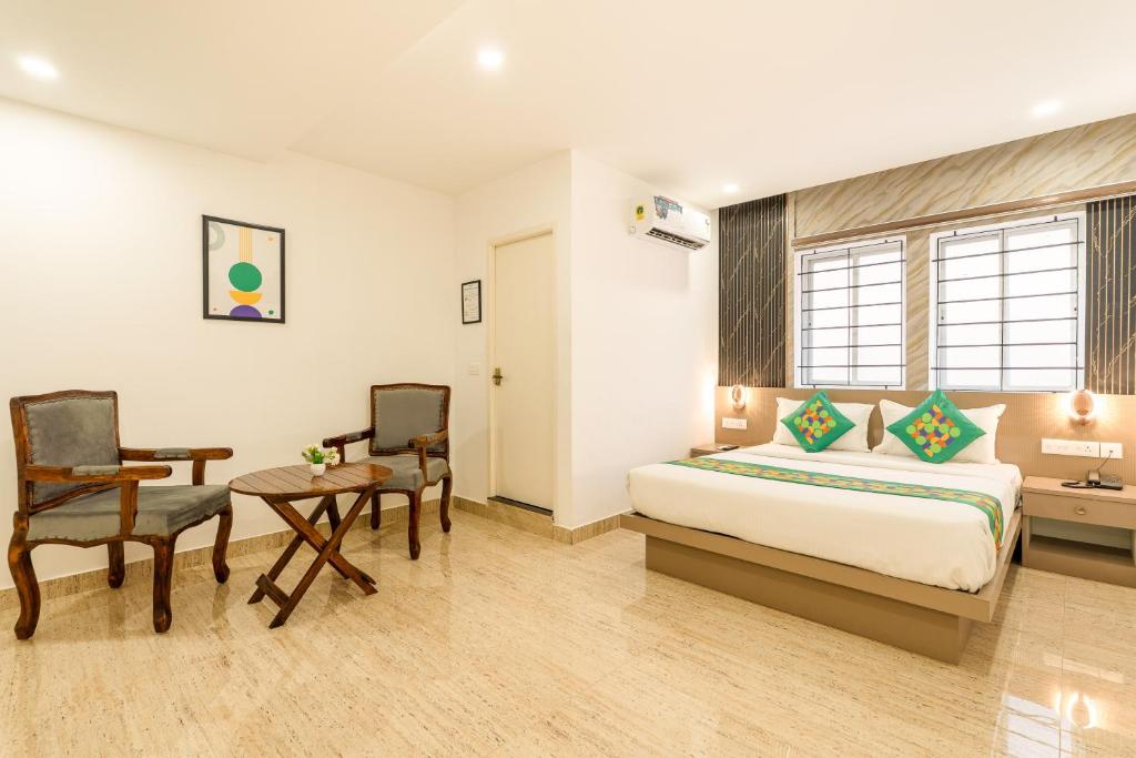 a bedroom with a bed and a table and chairs at Treebo Skyline in Mangalore
