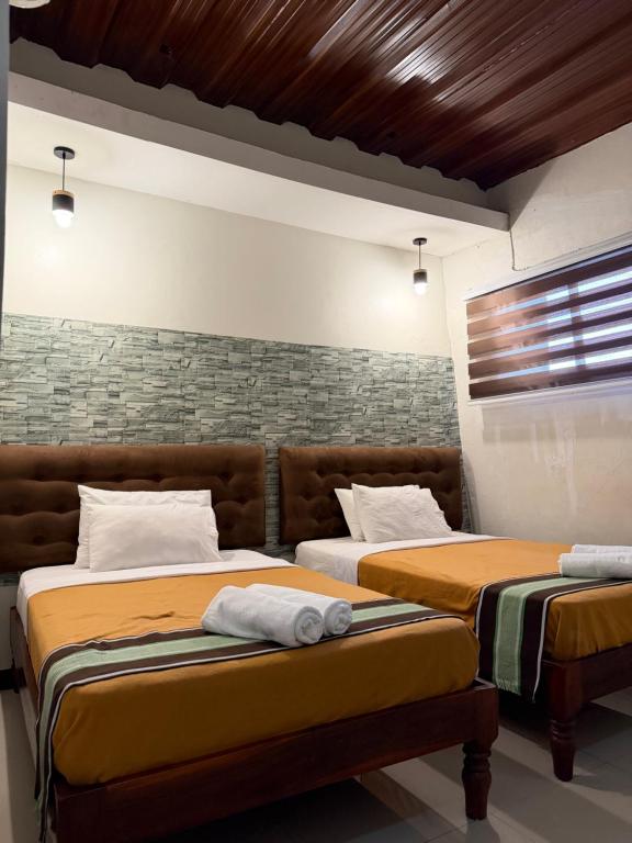 a bedroom with two beds and a brick wall at Bantay Viajeros Inn in San Julian Norte