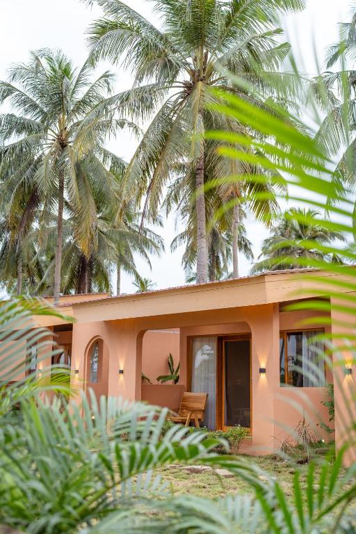 a pink house with palm trees in the background at Los Londos Batukaras in Cijulang Nusawiru Airport