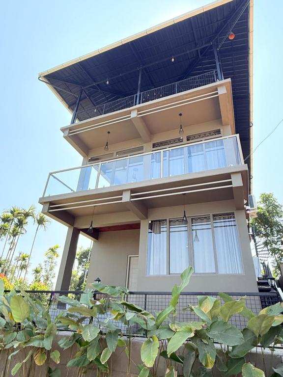 a house with a balcony on top of it at Valensa lake view in Kalpetta