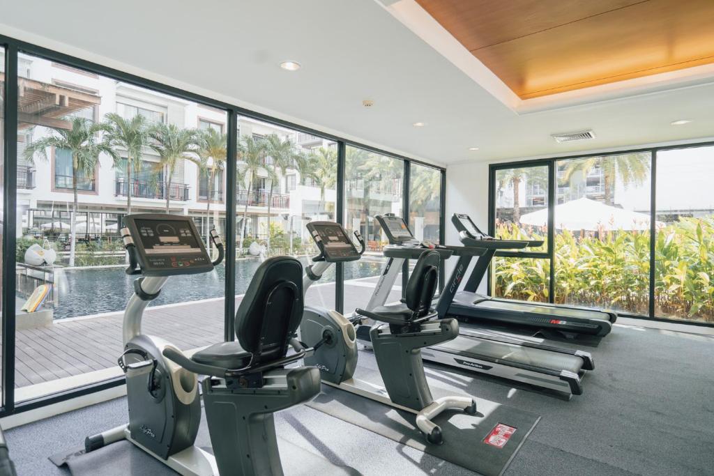 A bright gym with cardio machines beside floor-to-ceiling windows.