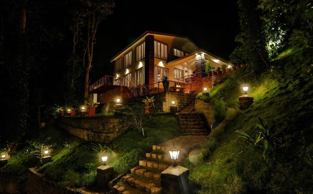 a house on a hill at night with lights at VOX Vanam Bungalow in Kodaikānāl