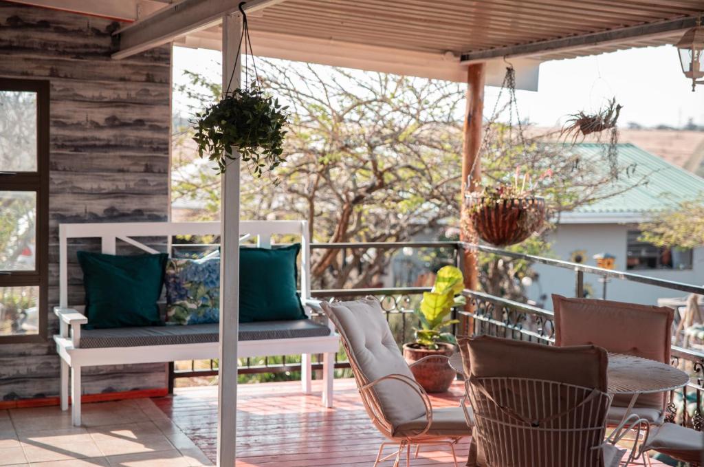 a porch with a bench and chairs and a table at Chilli cottage - off grid get away in Mkondeni
