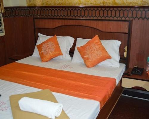 a bedroom with two beds with orange and white pillows at amb guest house in Chennai