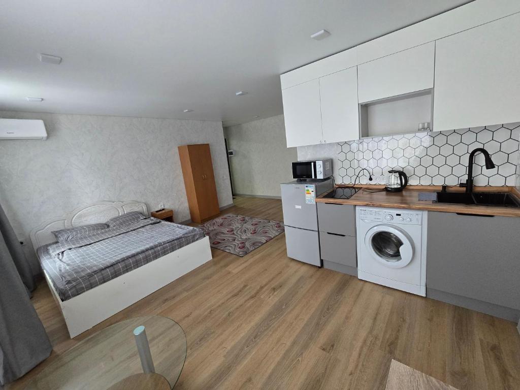 a bedroom with a bed and a kitchen with a washing machine at В Центре Экибастуза in Ekibastuz