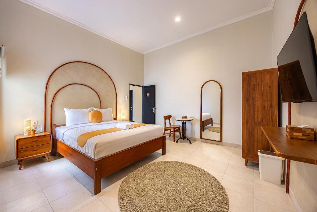 a bedroom with a bed and a table and a mirror at Cove Chara in Jimbaran