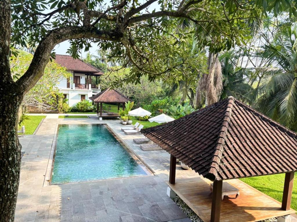 a resort with a swimming pool and a house at Bumi Kinar Heritage in Ubud