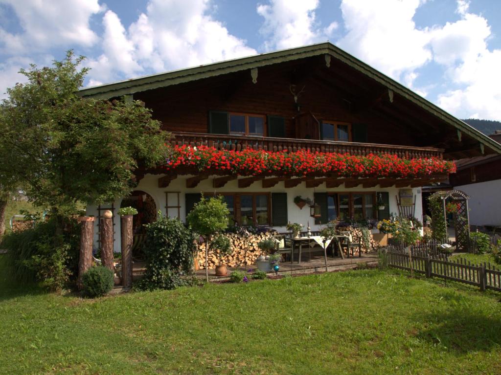 a house with red flowers on a balcony at Gästehaus Barbara Schwaiger - Chiemgau Karte in Inzell