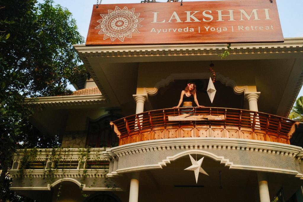 a woman standing on a balcony of a building at Lakshmi Ayurveda Retreat in Kovalam