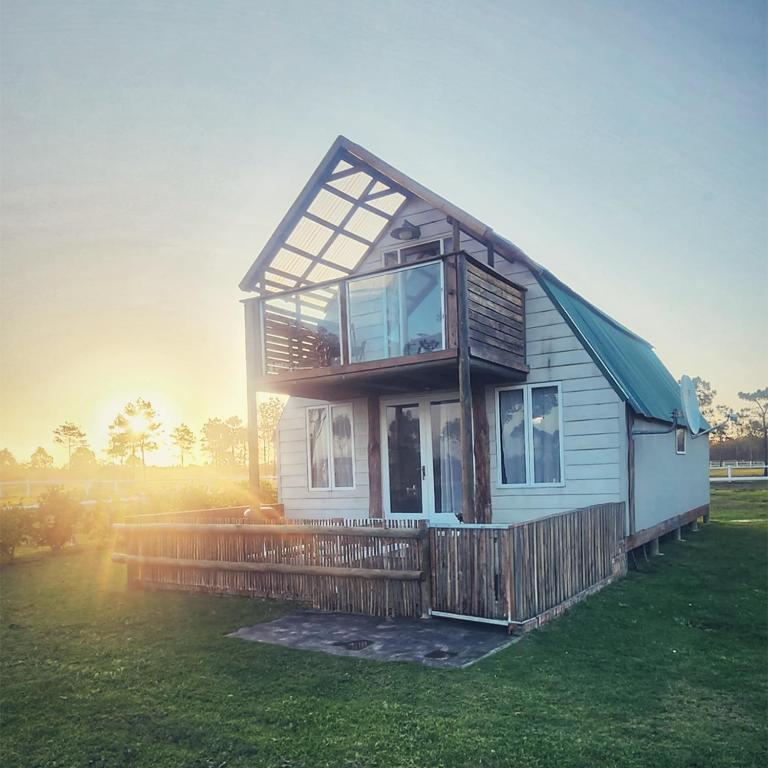 a small house on a lawn with the sun setting at TNiqua Stable Inn in Plettenberg Bay