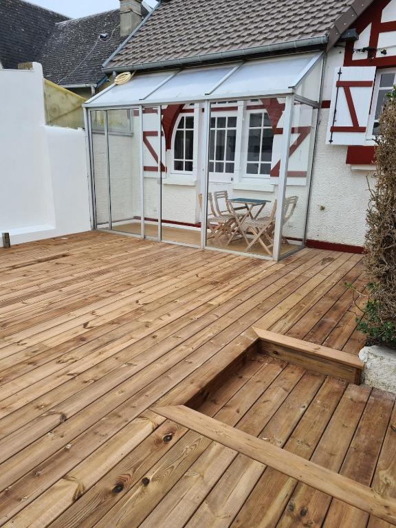 a wooden deck in front of a house at Charmante maison de bord de mer avec terrasse in Luc-sur-Mer