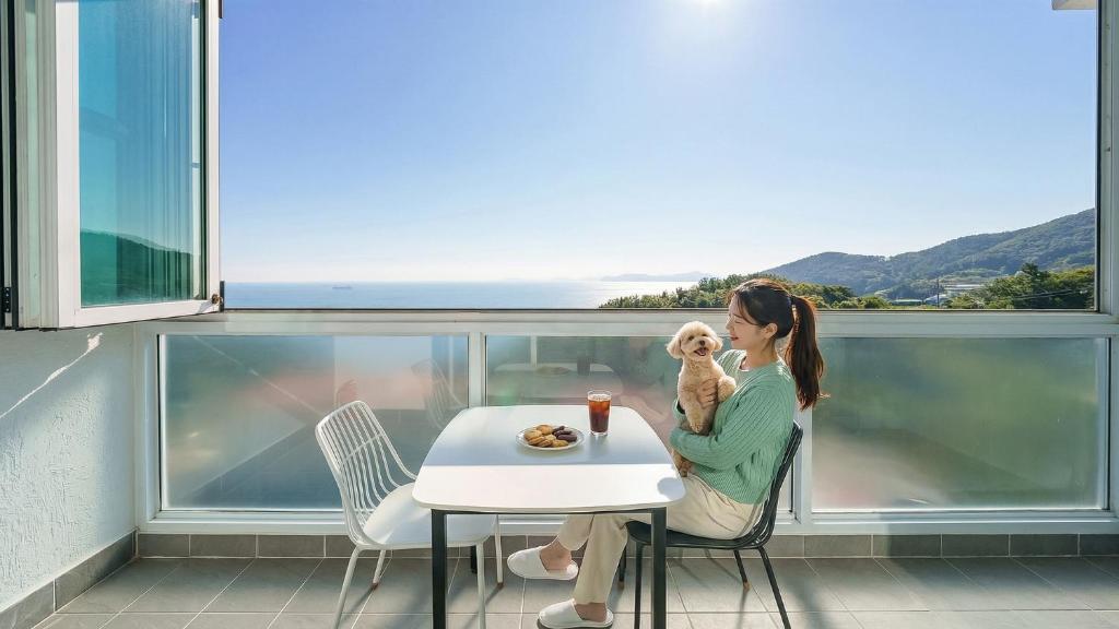 a woman sitting at a table with a teddy bear at Namhae Briant Oceanview Spa Pension in Namhae