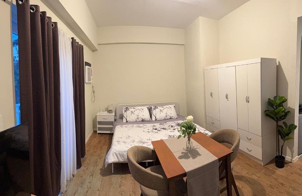 a bedroom with a bed and a table with chairs at Priscilla Suites Mactan by Amani Grand Resort in Mactan Cebu International