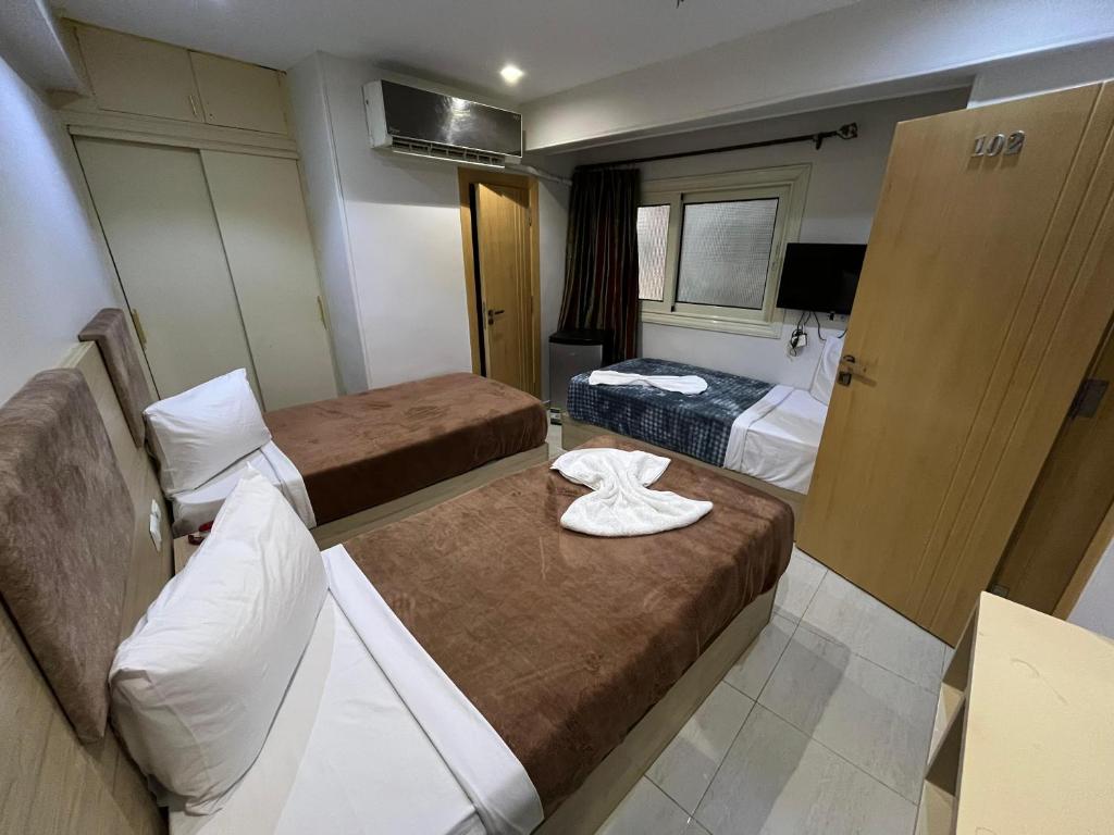 a small hotel room with two beds and a door at Bostan Hotel in Cairo